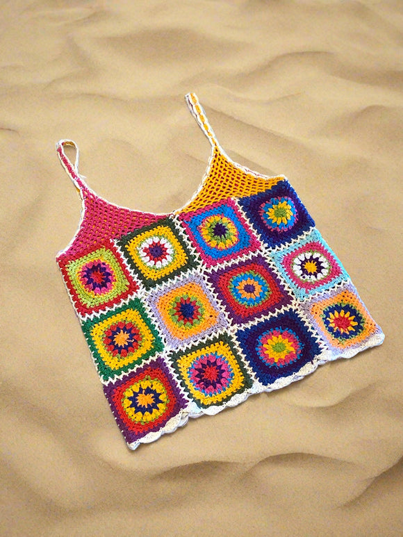 Colorful crocheted blanket with square patterns on a concrete surface