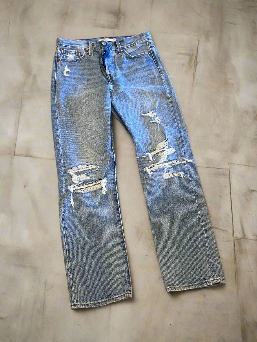 Pair of distressed blue jeans on a brown surface