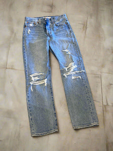 Pair of distressed blue jeans on a brown surface