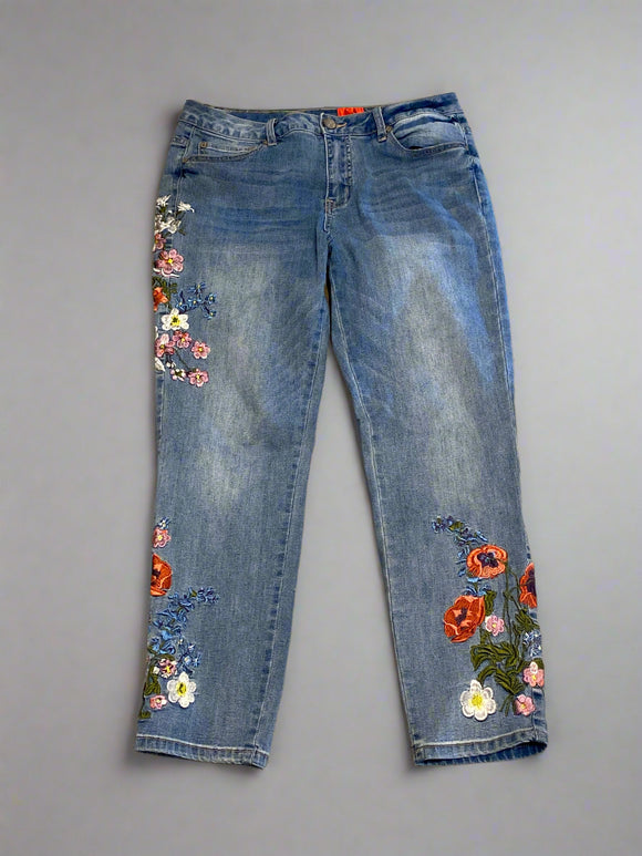 Blue jeans with floral embroidery on a concrete floor