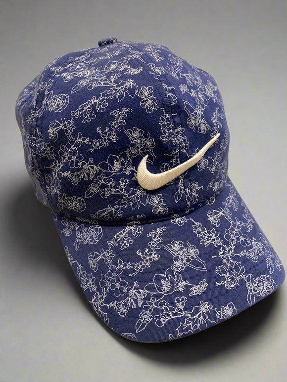 Blue floral-patterned pillow with a white Nike logo on a beige surface