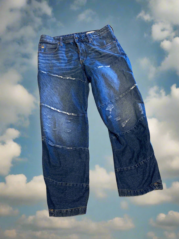 Pair of blue jeans with visible wear on a beige surface